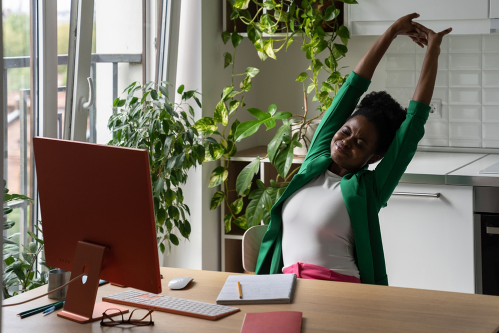 Lady stretching at her desk in the office.
